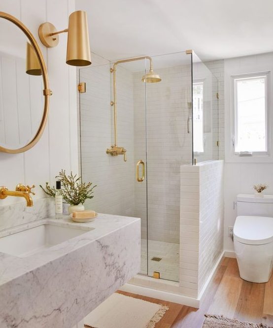 a chic and glam white bathroom with white tiles, a white marble floating sink and touches of gold for a shiny look