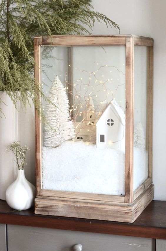 an oversized wodoen candleholder with faux snow, mini houses and churches, a mini bottle brush tree and lights