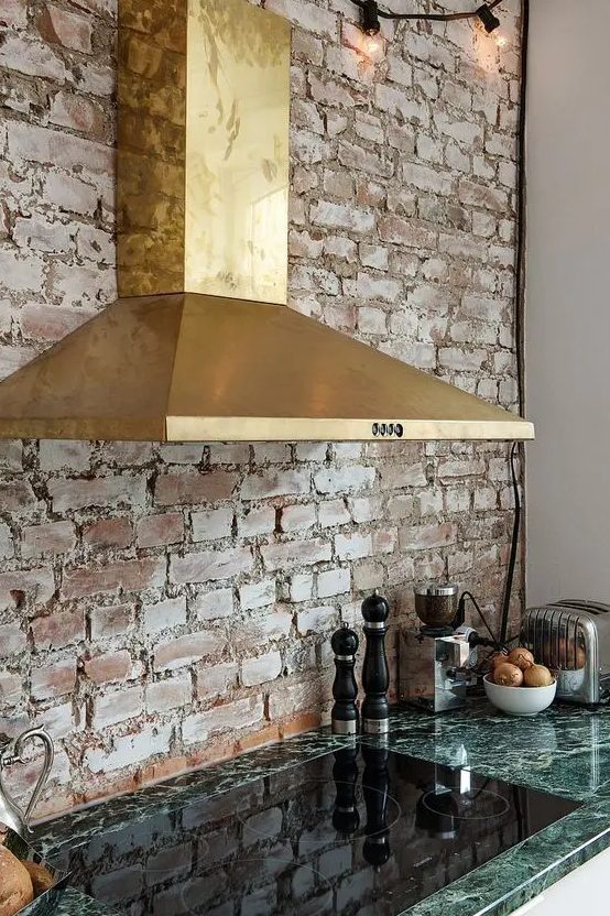 a gorgeous brass hood and a green marble countertop create a chic and bold look