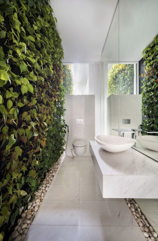 a truly biophilic bathroom done in neutrals and with a living wall and pebbles on the floor for a natural touch