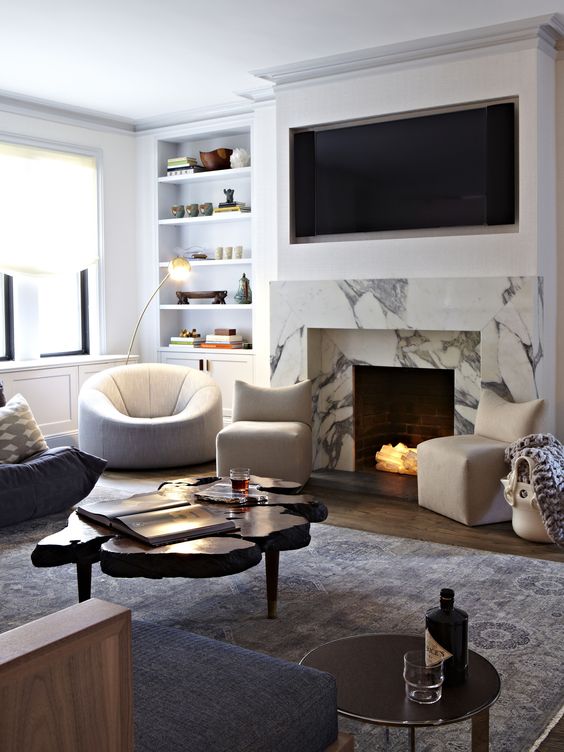 a-beautiful-living-room-with-built-in-shelves-black-and-white-chairs-a-living-edge-coffee-table-a-white-marble-fireplace.jpg