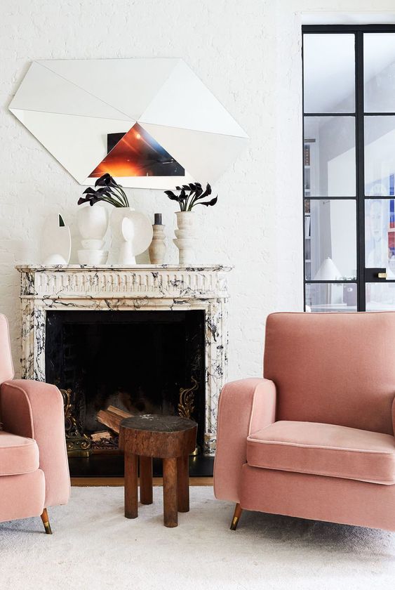 a-bold-and-edgy-space-with-a-marble-clad-fireplace-pink-chairs-a-side-table-white-vases-on-the-mantel-and-a-cool-mirror.jpg