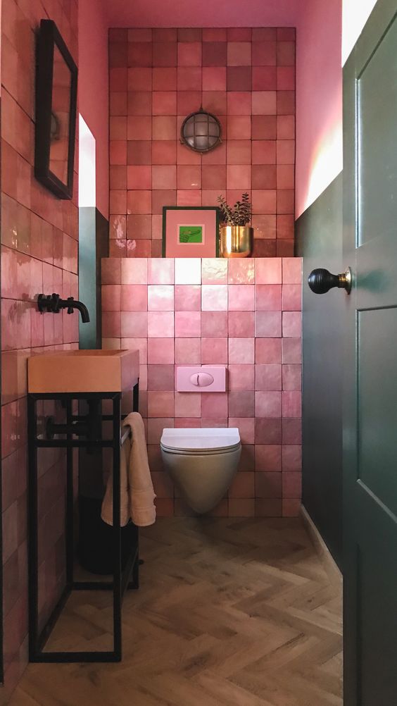 a bright mudroom with pink zellige tiles, a free standing pink sink, artworks and a plant in a gilded pot