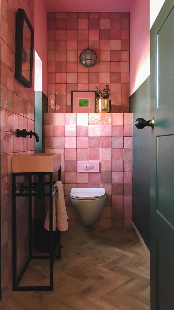 a bright mudroom with pink zellige tiles, a free-standing pink sink, artworks and a plant in a gilded pot