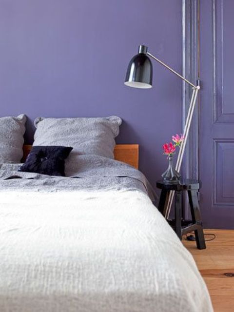 a chic periwinkle bedroom with a matching door, a stained bed with dip-dye bedding and a black nightstand with a black lamp