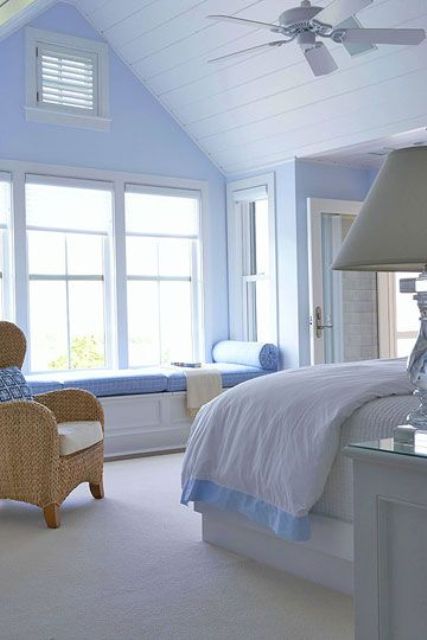 a coastal periwinkle bedroom with a white planked ceiling, white furniture with periwinkle upholstery, a woven chair and some neutral lamps and chandeliers
