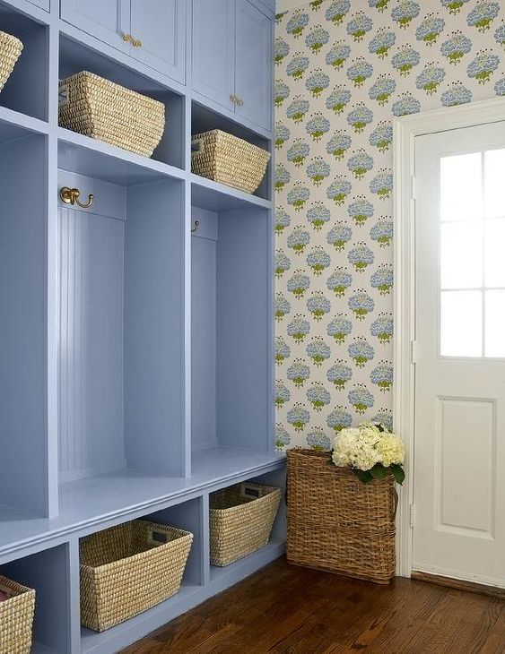 a cottage-style mudroom with printed floral wallpaper, a periwinkle storage unit with baskets for storage is a lovely idea