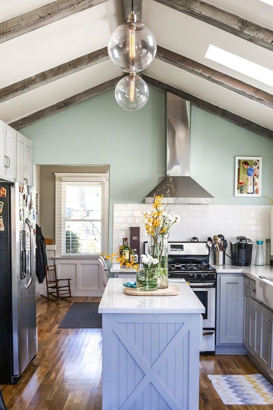 a cottage very peri kitchen with white countertops, white subway tiles, wooden beams on the ceiling and stainless steel appliances