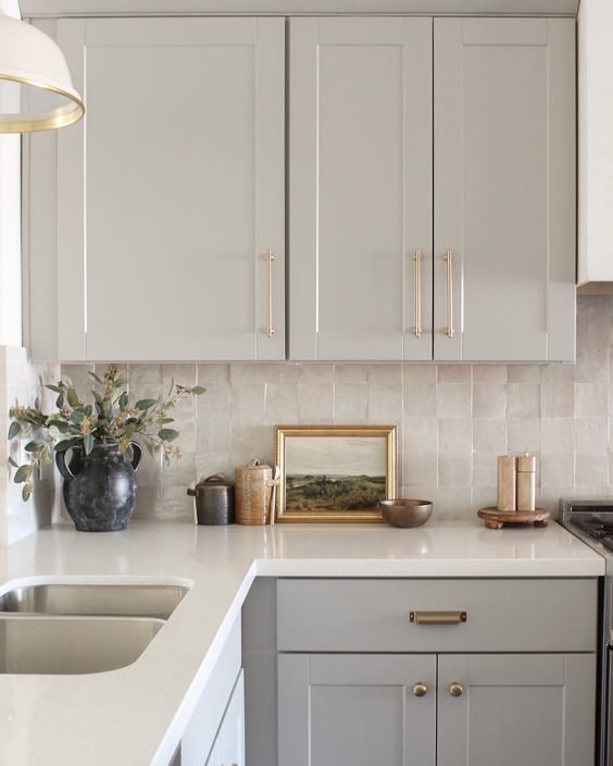 a grey kitchen with a neutral zellige tile backsplash, a white stone countertop and pendant lamps is chic and lovely