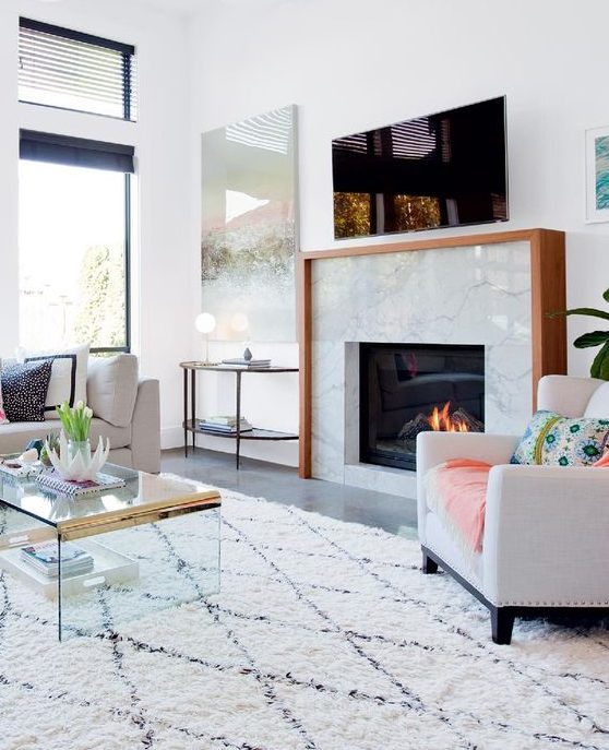 a light-filled and welcoming living room with a marble clad built-in fireplace with a wooden mantel
