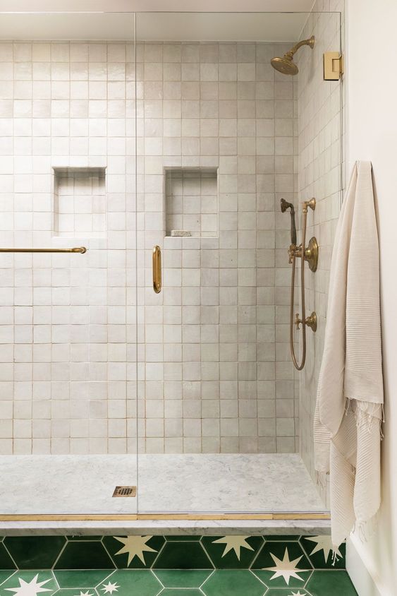 a lovely shower space clad with neutral zellige tiles and marble ones, with chic brass features for a touch of vintage in the space