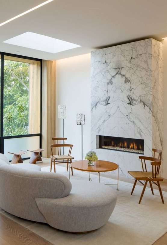 a modern refined living room with a white marble fireplace that warms up the whole space and makes it cozier