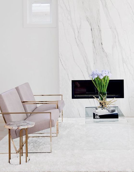 a neutral elegant space with a white marble clad fireplace, lavender chairs and touches of brass for more chic