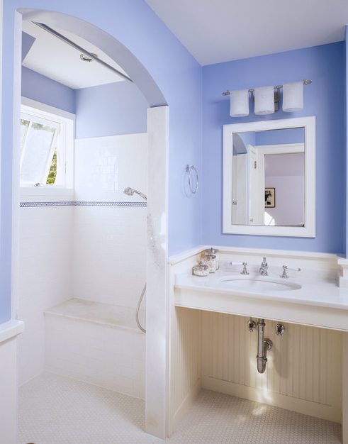 a periwinkle bathroom with neutral wainscoting and white tiles, white vintage appliances and a small window in the shower space
