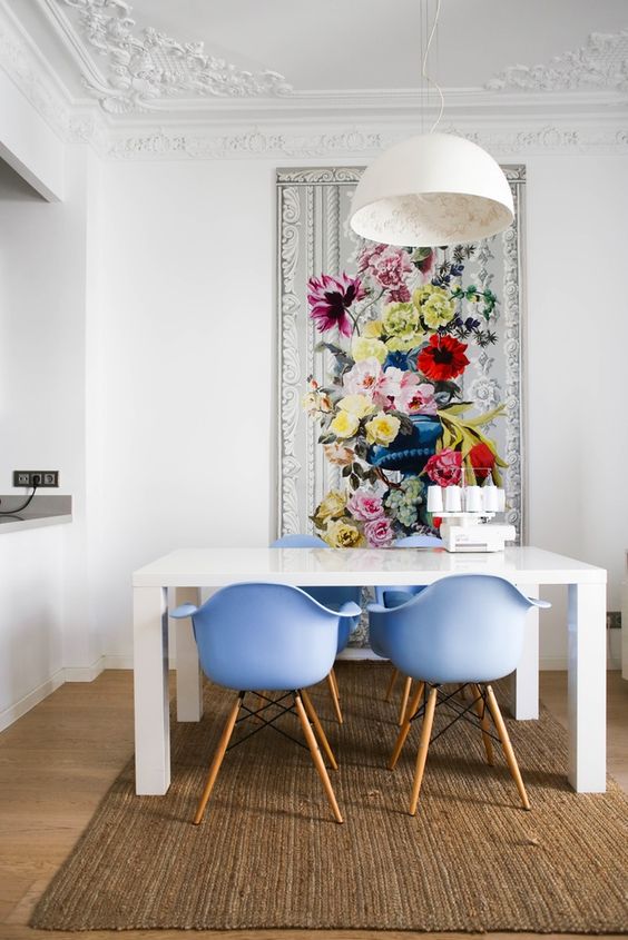 a refined dining space with a simple white table, periwinkle chairs and a bold floral artwork that sets the tone in the room