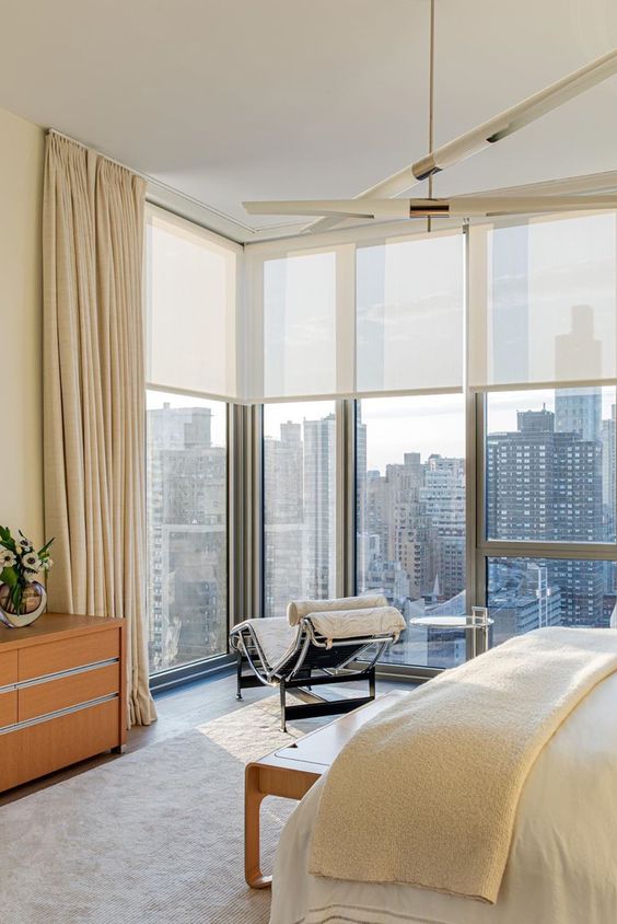 a refined modern bedroom with a fantastic view, with semi sheer shades and beautiful neutral draperies to enjoy the views or get privacy when needed