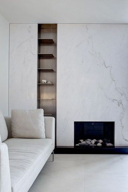 a sophisticated neutral living room in contemporary style, with a white marble fireplace, built-in shelves and a white sofa