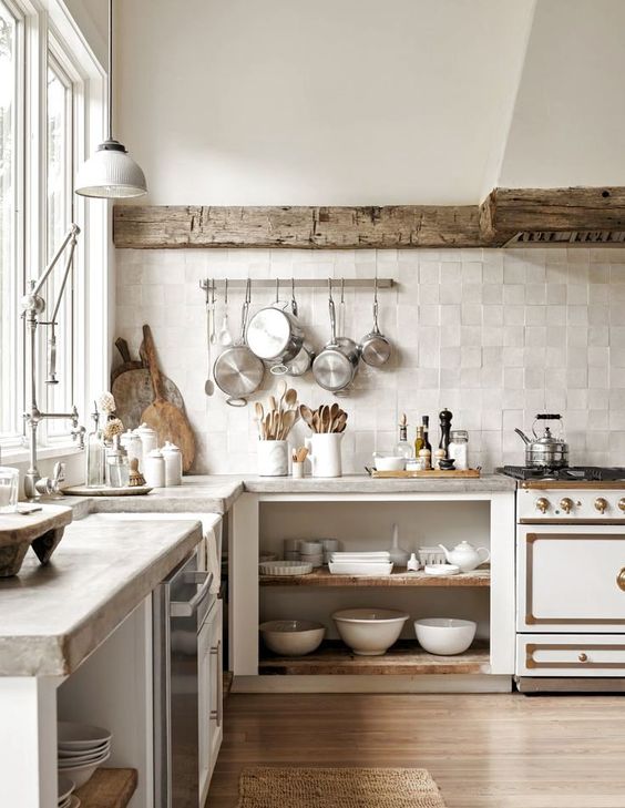 a wabi wabi kitchen with open cabinetry, a reclaimed wooden beam covering the hood, concrete countertops and a neutral zellige tile backsplash