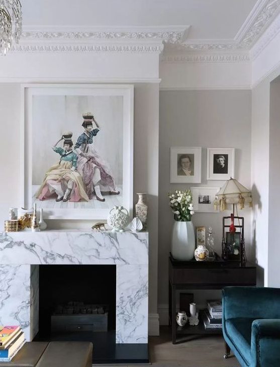 a whimsical vintage-inspired living room with a non-working fireplace clad with white marble and beautiful artworks