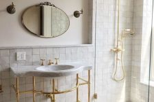 an elegant neutral bathroom accented with neutral zellige tiles, with a free-standing sink and gold fixtures