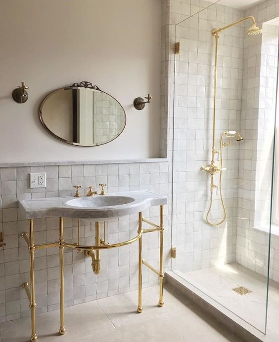 an elegant neutral bathroom accented with neutral zellige tiles, with a free-standing sink and gold fixtures