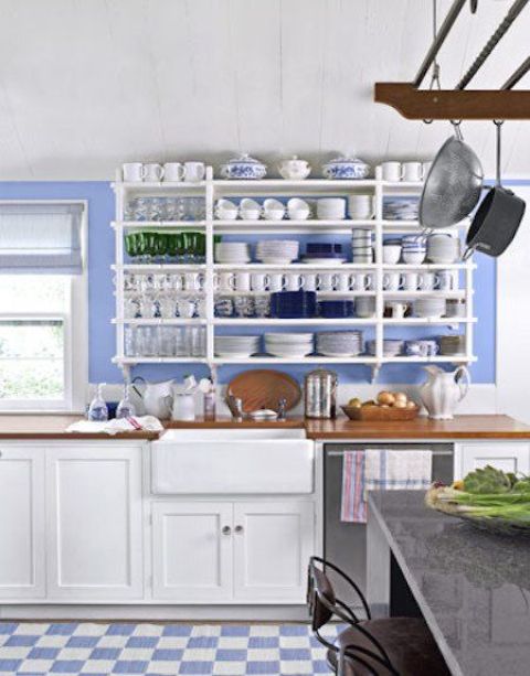 an exquisite and chic kitchen with periwinkle walls, white cabinets and an open shelving unit, a kitchen island with a concrete countertop