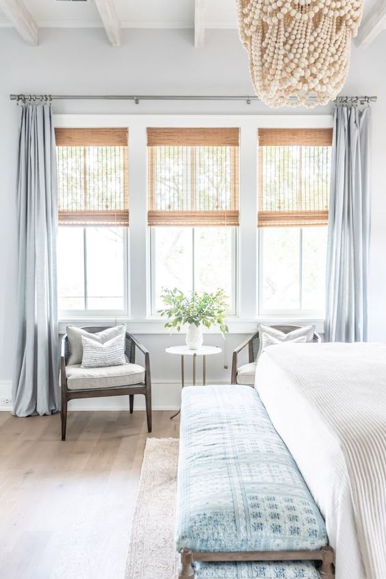 semi sheer woven shades and pastel blue curtains are a perfect match for a coastal bedroom done in the same pastel blues