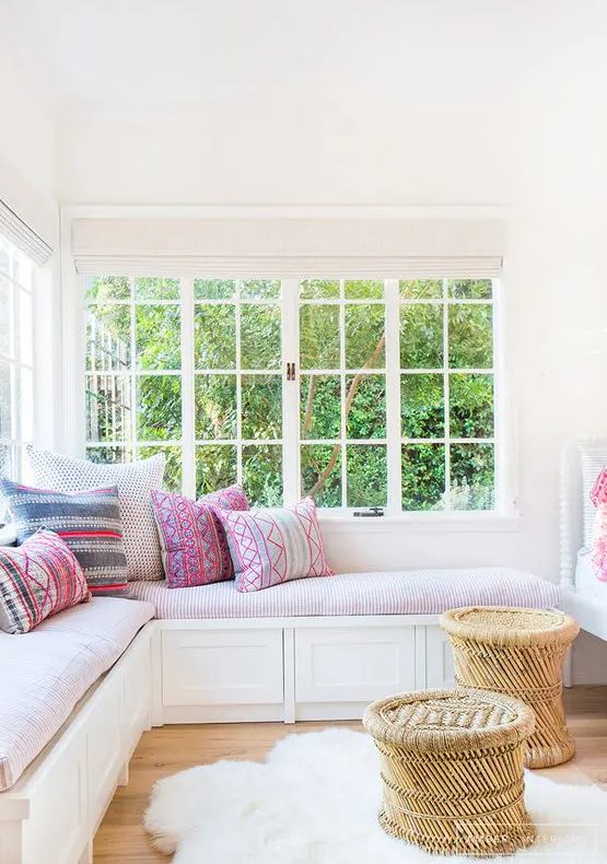 a cozy and inviting nook with a corner window, a corner daybed with colorful pillows and rattan stools is very chic and lovely