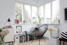 04 a lovely Nordic nook with a corner window, a windowsill used for storage, a black chair and a bookshelf is a very cozy corner