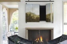 08 a cozy sitting nook with a real fireplace with a metal screen and a TV hidden behind an artwork that can be folded to watch TV