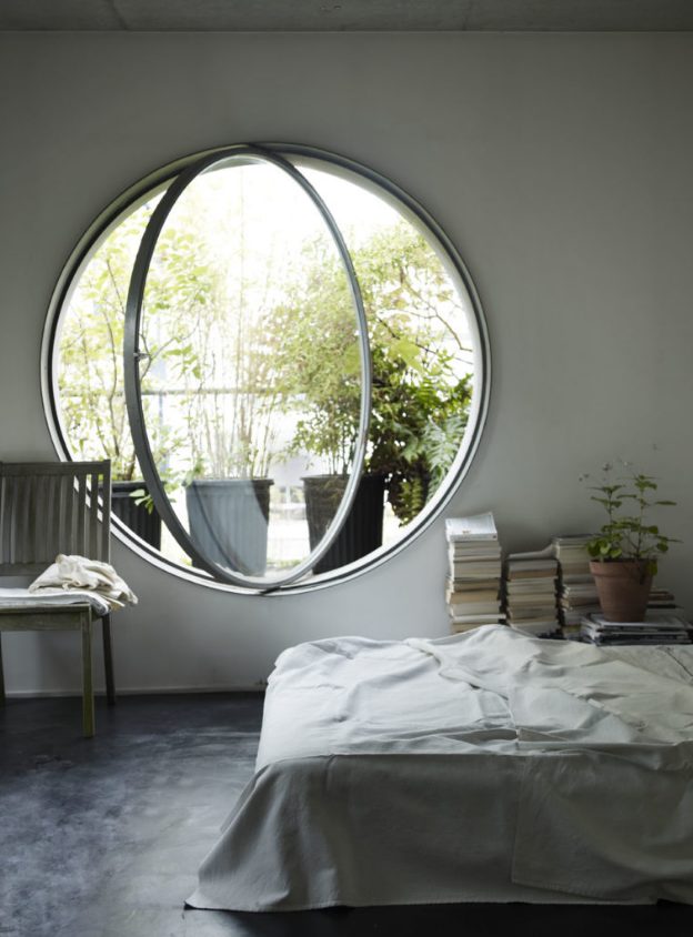 a neutral and airy bedroom done with a round pivot window, which allows fresh air in easily