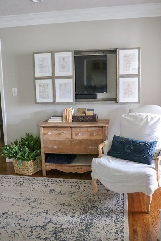 a farmhouse living room with vintage furniture, a reclaimed wooden vanity, a TV hidden behind a vintage poster gallery wall
