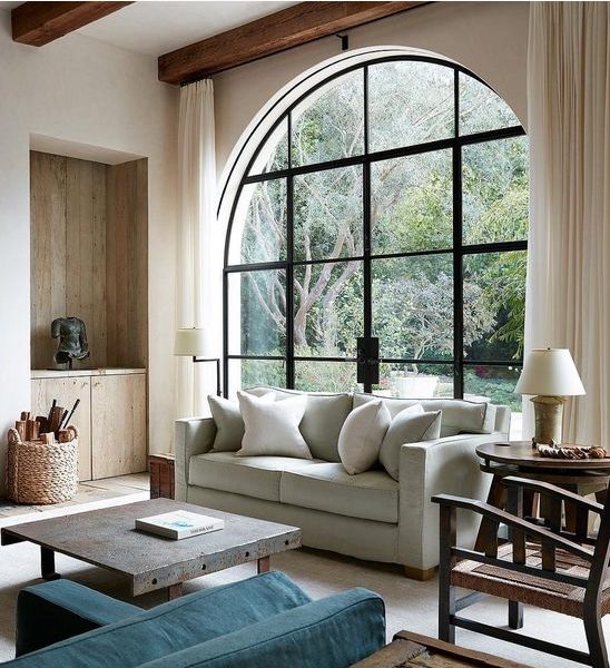 a contemporary living room with an oversized black frame arched window that includes an access to the garden