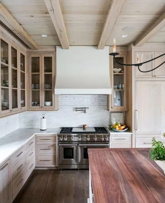 a catchy and welcoming kitchen with a whitewashed ceiling and cabinets, with a reclaimed wood floor and a kitchen island with a reddish countertop
