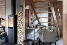 14 a cozy Scandi space with a hearth, a grey stained planked floor, rich-stained planked walls and a staircase and grey furniture is welcoming