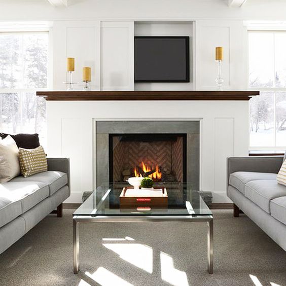 a modern neutral living room with a TV over the fireplace hidden with a sliding panel that is a cool and lovely solution