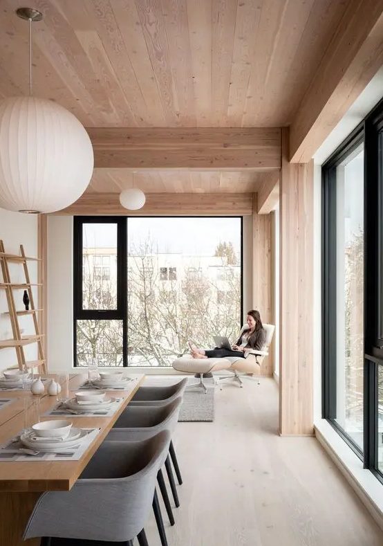 a luxurious minimalist dining room with much natural light, a whitewashed floor and warm and light tones of wood all over the space