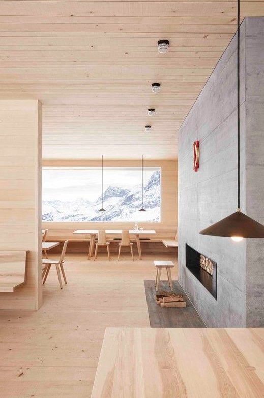 a beautiful chalet space fully clad with blonde wood including blonde wood furniture and a concrete clad fireplace