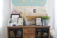 18 a stylish farmhouse space with a reclaimed wood storage unit, greenery, artwork and a large world map that hides the TV easily and effortlessly