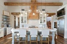 21 a white farmhouse kitchen with white cabinets, a refined kitchen island, a reclaimed wooden floor, light-stained wooden beams and a ceiling