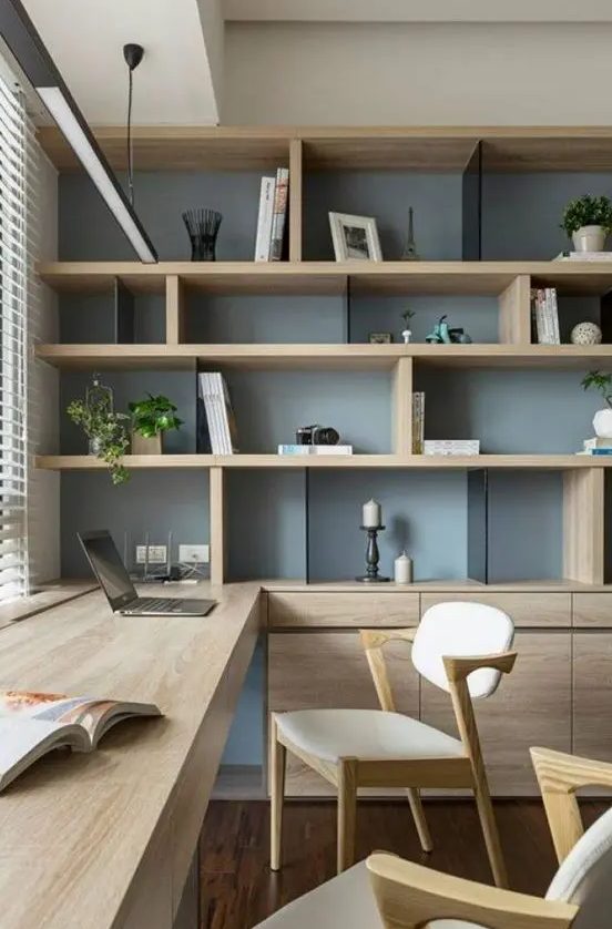 a chic contemporary home office with a storage unit that takes a whole wall, with open and closed storage compartments, a built in desk and chic modern chairs