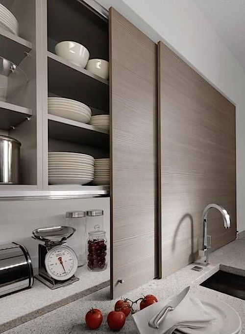 sleek sliding doors hiding open storage cabinets with not only appliances but also much other stuff is a genius idea