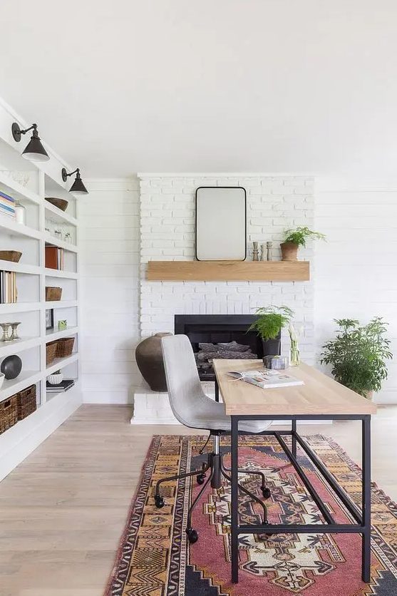 a cool modern country home office with a white brick fireplace, a large storage unit, a desk and a bold rug, potted plants