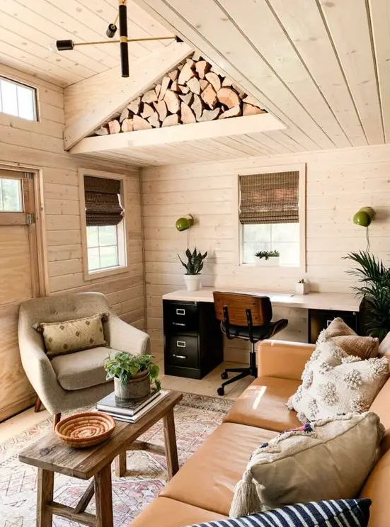 a cozy farmhouse home office with a leather sofa a cool chair a contrasting desk and everything around clad with wood