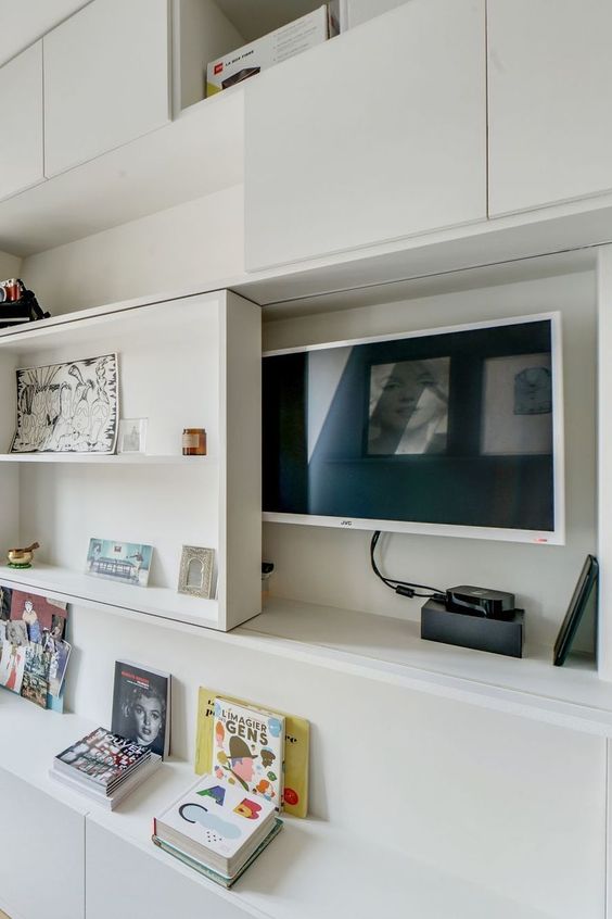 a TV hidden under a shelving unit that can slide and let you watch TV   this is a stylish and cool idea