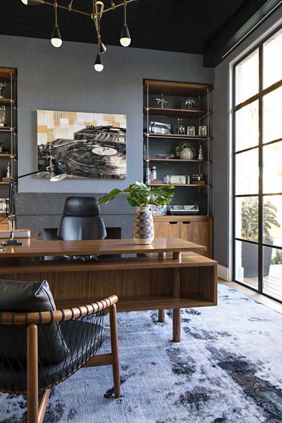 a refined modern home office with built-in storage units, a stained desk with two tabletops, black leather chairs