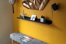 32 a bold entryway with a sunny yellow accent wall, a black shelf and a wall-mounted planter plus unique mirrors