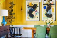 33 a colorful dining room with bold yellow walls, a stained table and credenza, green chairs and an elegant chandelier
