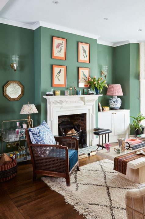 an elegant living room with calming green walls, a fireplace with a vintage mantel, a gallery wall and dark and light furniture
