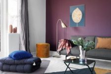 35 a bold living room with an eggplant accent wall, grey furniture, a bold color block rug and touches of gold
